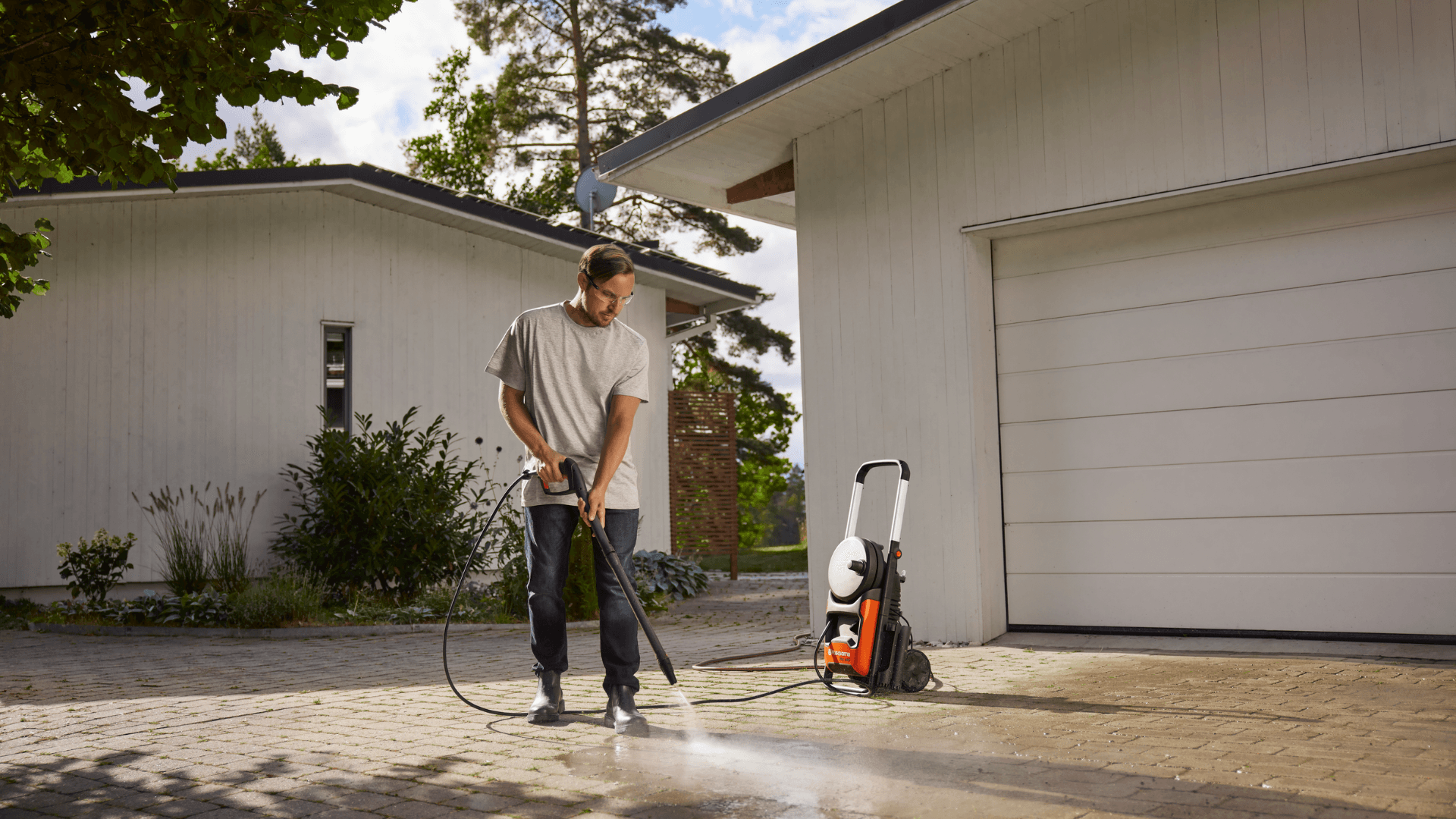 man cleaning driveway with pressure washer